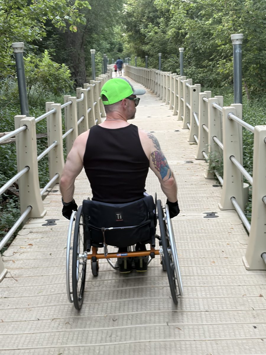 The host wheeling away down a wooden boardwalk lined with trees.